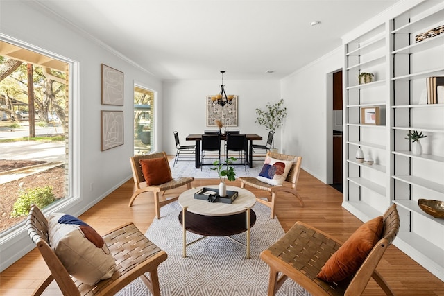 sitting room with ornamental molding, a chandelier, baseboards, and light wood finished floors