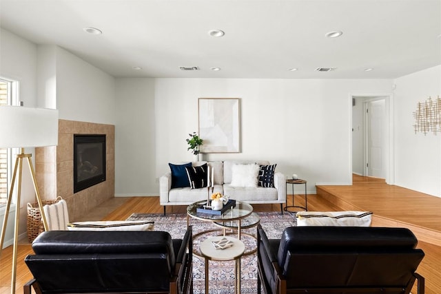 living room featuring a fireplace, recessed lighting, visible vents, wood finished floors, and baseboards