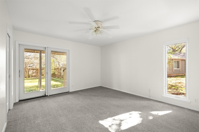 empty room with carpet floors, a ceiling fan, and baseboards