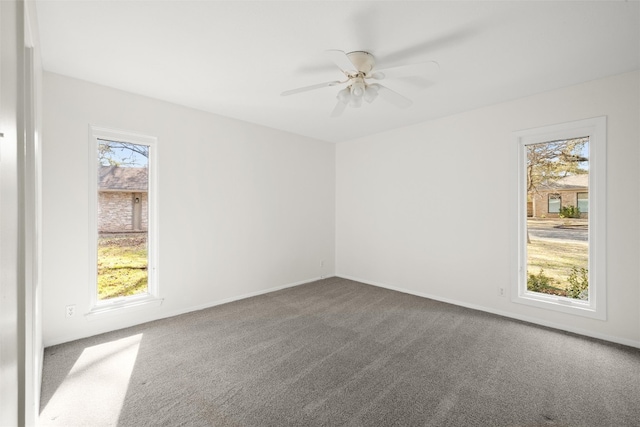 carpeted spare room featuring a ceiling fan and baseboards