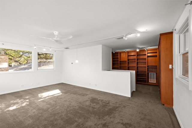 carpeted spare room with track lighting, a ceiling fan, and baseboards