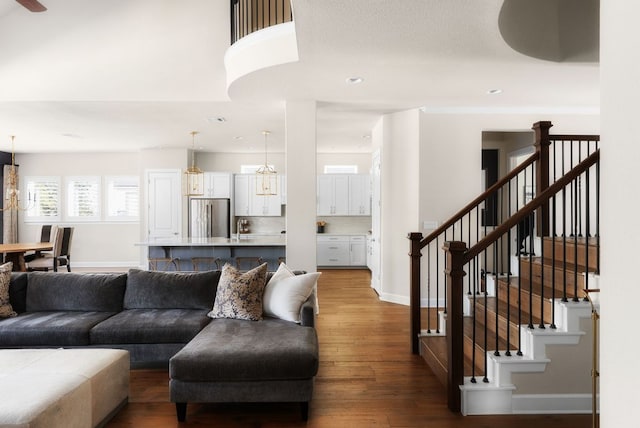 living area featuring recessed lighting, hardwood / wood-style floors, an inviting chandelier, baseboards, and stairs