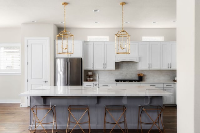 kitchen with tasteful backsplash, black gas cooktop, high quality fridge, a sink, and wood finished floors