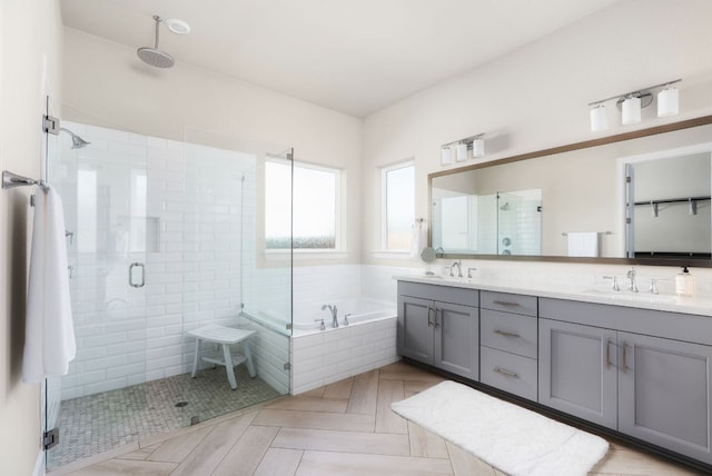 bathroom featuring a bath, a stall shower, double vanity, and a sink