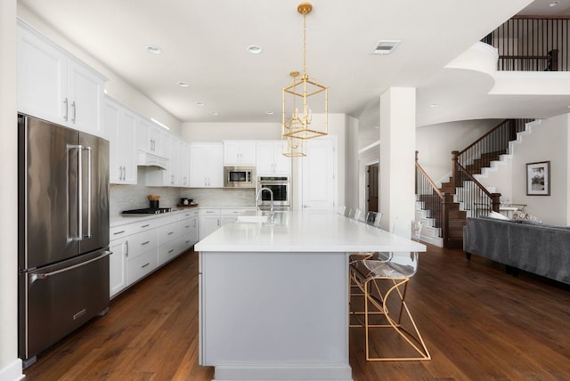 kitchen featuring stainless steel appliances, light countertops, dark wood finished floors, and visible vents