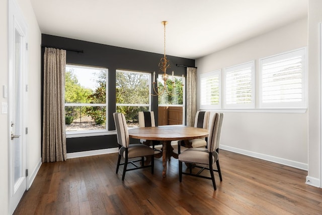 dining space featuring dark wood-style floors, a notable chandelier, baseboards, and a wealth of natural light