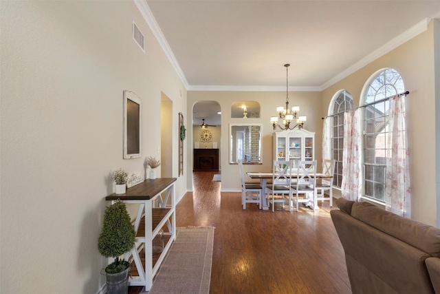 dining area featuring crown molding, visible vents, wood finished floors, a chandelier, and baseboards