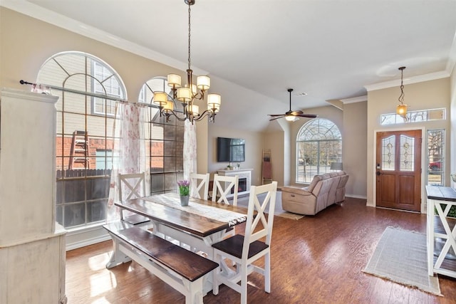 dining space with crown molding, lofted ceiling, an inviting chandelier, wood finished floors, and baseboards