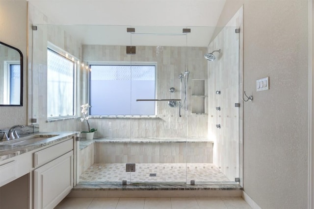 bathroom with a textured wall, a shower stall, and vanity