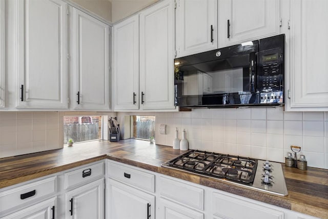 kitchen with black microwave, stainless steel gas cooktop, white cabinets, wooden counters, and backsplash