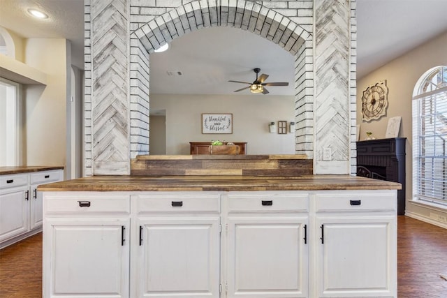 kitchen featuring butcher block countertops, visible vents, a ceiling fan, white cabinetry, and dark wood-style floors