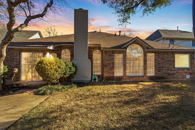 view of front of home featuring a yard, a chimney, and brick siding