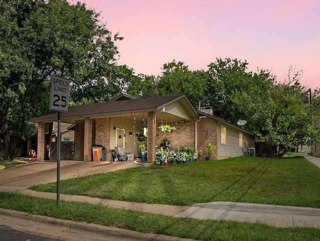single story home with brick siding, a carport, a front yard, and concrete driveway