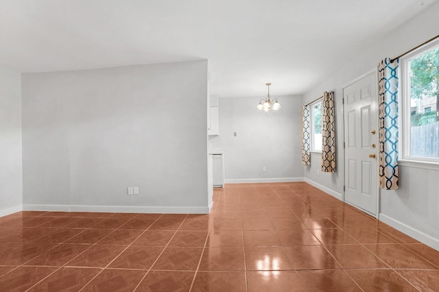 tiled entrance foyer featuring baseboards and a chandelier