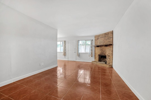 unfurnished living room with a brick fireplace, baseboards, and tile patterned flooring