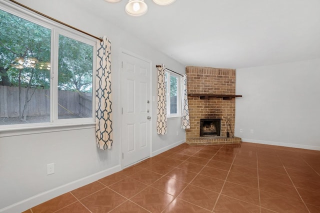 unfurnished living room with tile patterned flooring, baseboards, and a brick fireplace