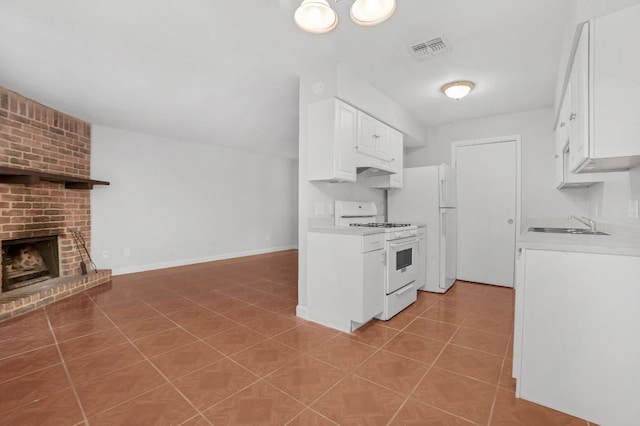 kitchen featuring a fireplace, white appliances, light countertops, white cabinetry, and visible vents