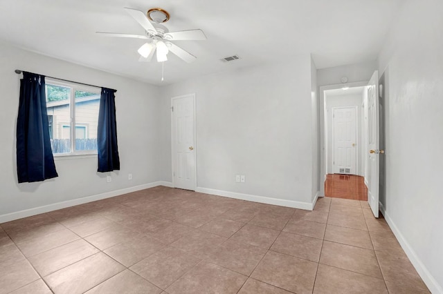 unfurnished bedroom featuring visible vents, a ceiling fan, baseboards, and light tile patterned floors