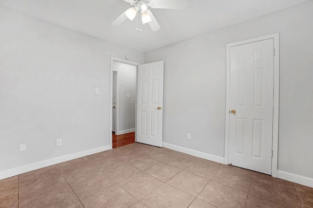 unfurnished bedroom with light tile patterned flooring, baseboards, and a ceiling fan