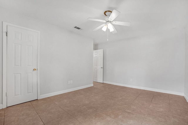 spare room featuring a ceiling fan, baseboards, visible vents, and tile patterned floors