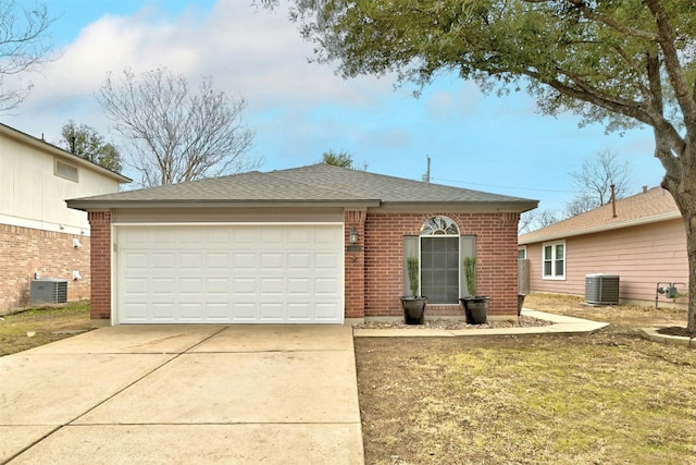 single story home with concrete driveway, central AC unit, an attached garage, and brick siding