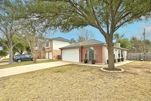 traditional-style house featuring brick siding, a chimney, concrete driveway, an attached garage, and fence