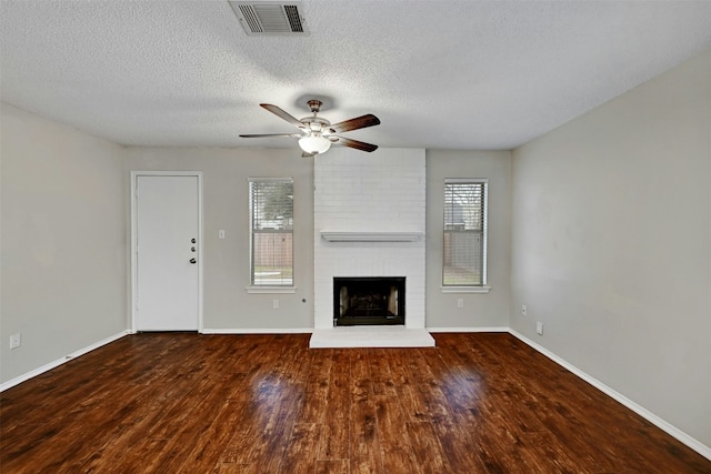 1807 Hollow Tree Blvd, Round Rock, TX 78681 - unfurnished living room with plenty of natural light, ceiling fan, wood finished floors, a textured ceiling, and a brick fireplace