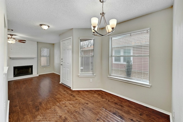 1807 Hollow Tree Blvd, Round Rock, TX 78681 - unfurnished dining area with a chandelier, dark wood-type flooring, a textured ceiling, ceiling fan, and a fireplace