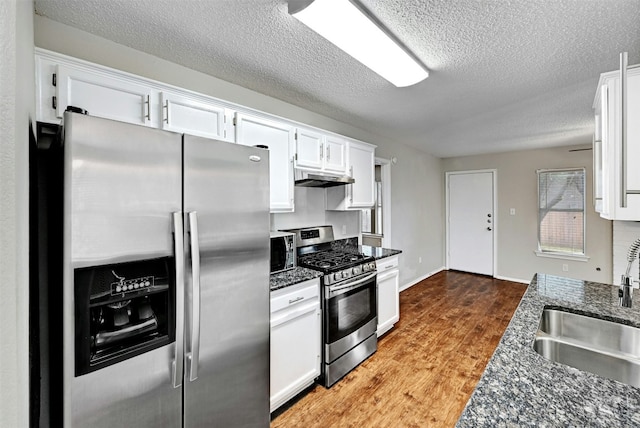 1807 Hollow Tree Blvd, Round Rock, TX 78681 - kitchen featuring appliances with stainless steel finishes, under cabinet range hood, white cabinetry, a textured ceiling, and dark stone counters