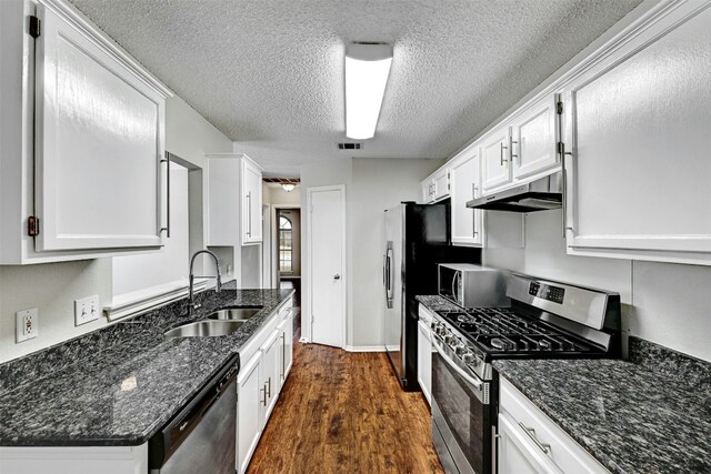 1807 Hollow Tree Blvd, Round Rock, TX 78681 - kitchen with stainless steel appliances, under cabinet range hood, white cabinets, dark wood finished floors, and a textured ceiling