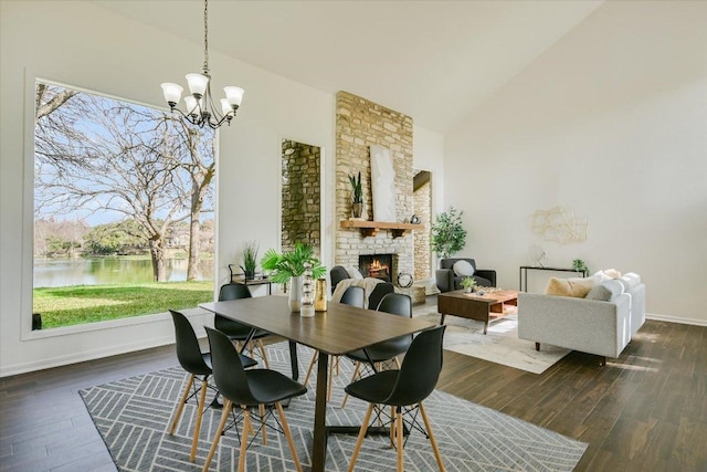 dining space featuring high vaulted ceiling, dark wood-style flooring, a fireplace, and a water view