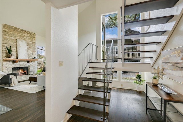 stairway with baseboards, wood finished floors, and a stone fireplace