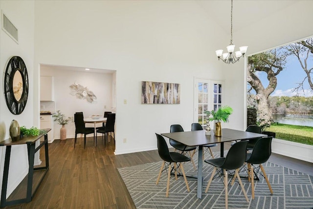 dining space featuring dark wood-style flooring, visible vents, a towering ceiling, and a healthy amount of sunlight