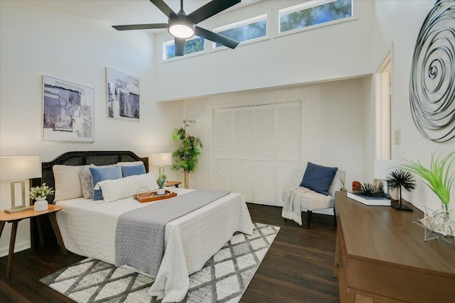 bedroom featuring a closet, ceiling fan, a towering ceiling, and wood finished floors