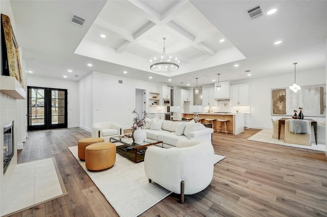 360 Judy Dr, Dripping Springs, TX 78620 - living room with coffered ceiling, visible vents, a chandelier, a fireplace, and light wood-type flooring