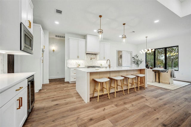 360 Judy Dr, Dripping Springs, TX 78620 - kitchen with light wood-style flooring, visible vents, stainless steel microwave, tasteful backsplash, and recessed lighting