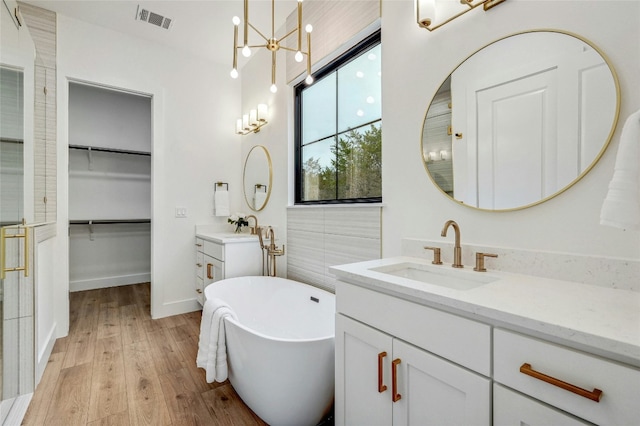 360 Judy Dr, Dripping Springs, TX 78620 - bathroom featuring a sink, wood finished floors, visible vents, a soaking tub, and two vanities
