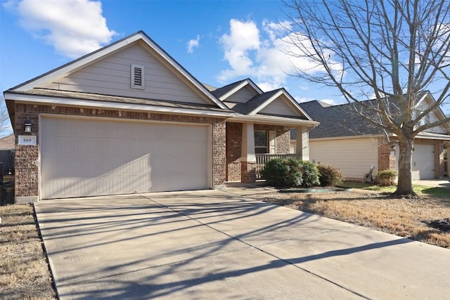 view of front of home featuring a garage, concrete driveway, brick siding, and a porch