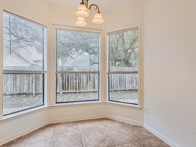 unfurnished dining area featuring baseboards, light tile patterned flooring, and a notable chandelier