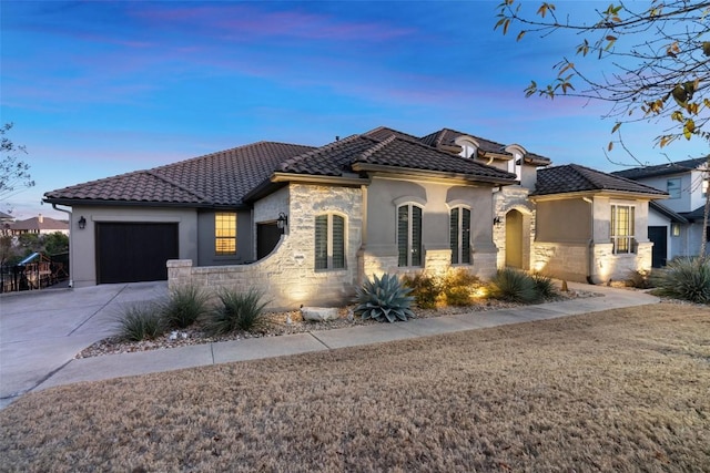 view of front of property featuring a garage, stone siding, a tile roof, and driveway