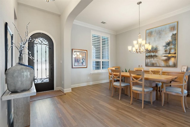 foyer entrance featuring arched walkways, wood finished floors, visible vents, baseboards, and ornamental molding