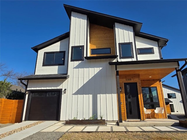 contemporary house featuring a garage, board and batten siding, and fence