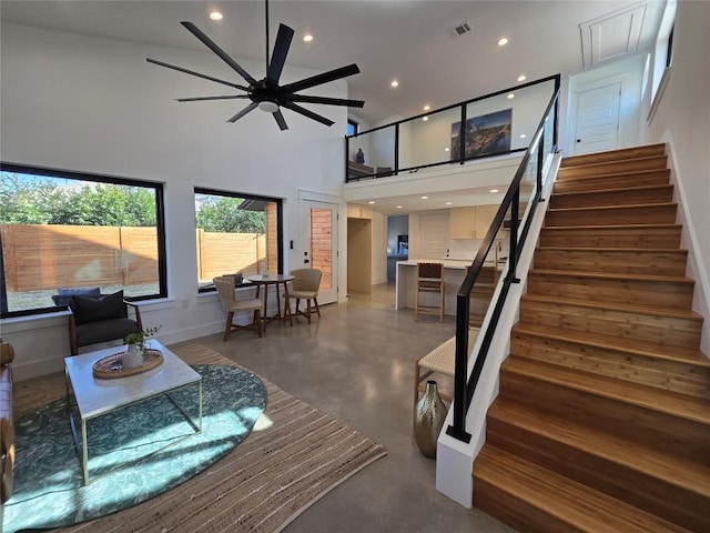 living room featuring visible vents, a towering ceiling, stairs, concrete flooring, and recessed lighting