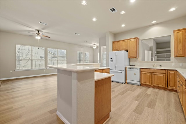 kitchen with white appliances, visible vents, a kitchen island, light countertops, and light wood-type flooring