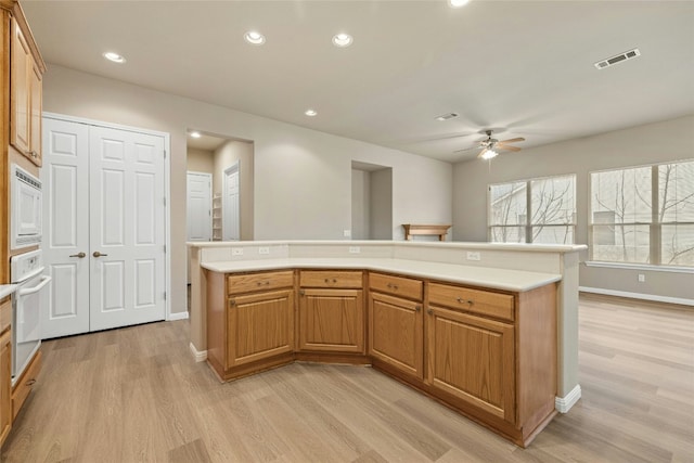 kitchen with light wood-type flooring, light countertops, white appliances, and visible vents