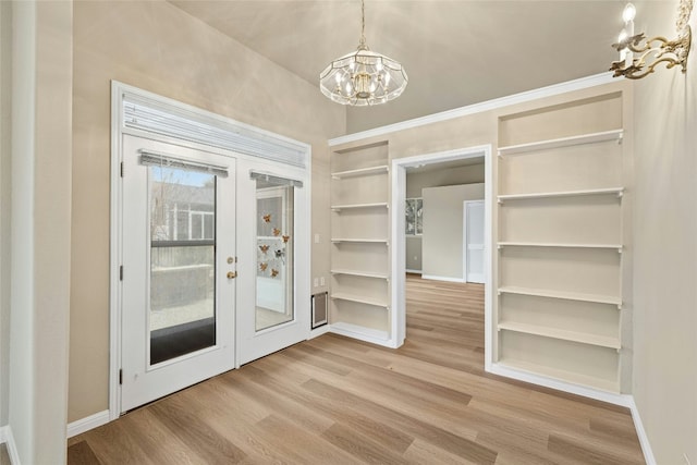 unfurnished dining area with baseboards, french doors, an inviting chandelier, and light wood-style floors