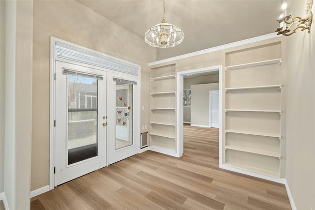 122 Durango Trl, Georgetown, TX 78633 - unfurnished dining area featuring a chandelier, french doors, wood finished floors, built in shelves, and baseboards