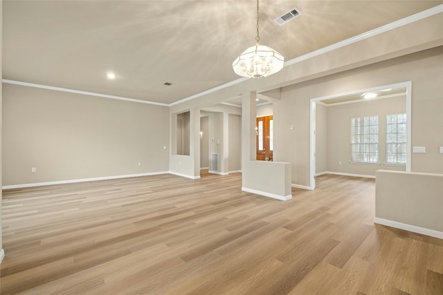 spare room featuring a notable chandelier, visible vents, baseboards, light wood-type flooring, and crown molding