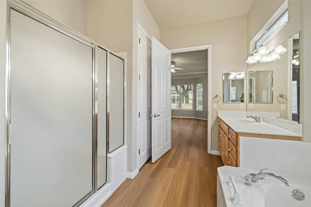 bathroom with a shower stall, vanity, wood finished floors, baseboards, and a bath