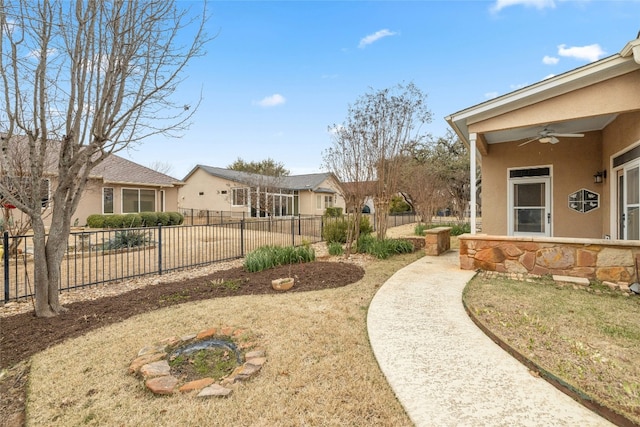 view of yard featuring a ceiling fan, a residential view, and fence